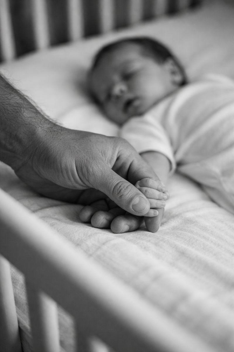 father holding the hand of his baby